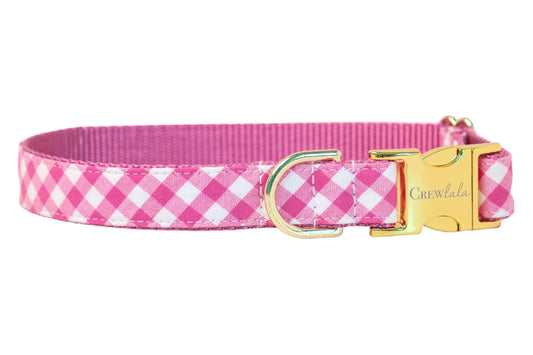 Bright fuchsia and white plaid fabric dog collar backed by durable pink nylon webbing. Accented with gold-finish hardware including a branded buckle and secure leash ring.