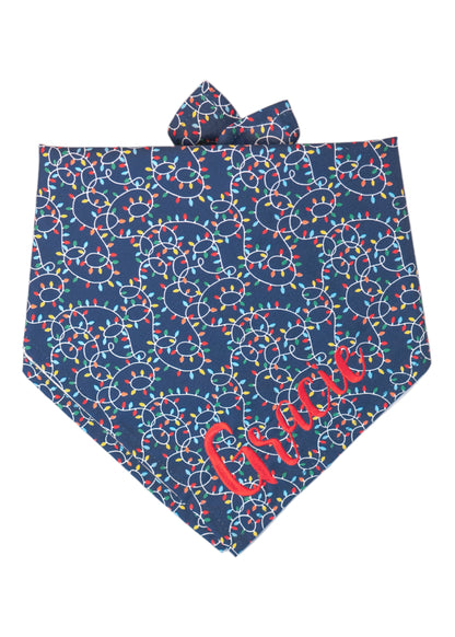 Holiday dog bandana in dark navy fabric decorated with bright string lights in festive colors. The swirling cords weave across the fabric in a tangled, fun design. Folded in a triangular shape with simple tie ends for a secure and adjustable fit. The name "Gracie" is embroidered on the bottom right.