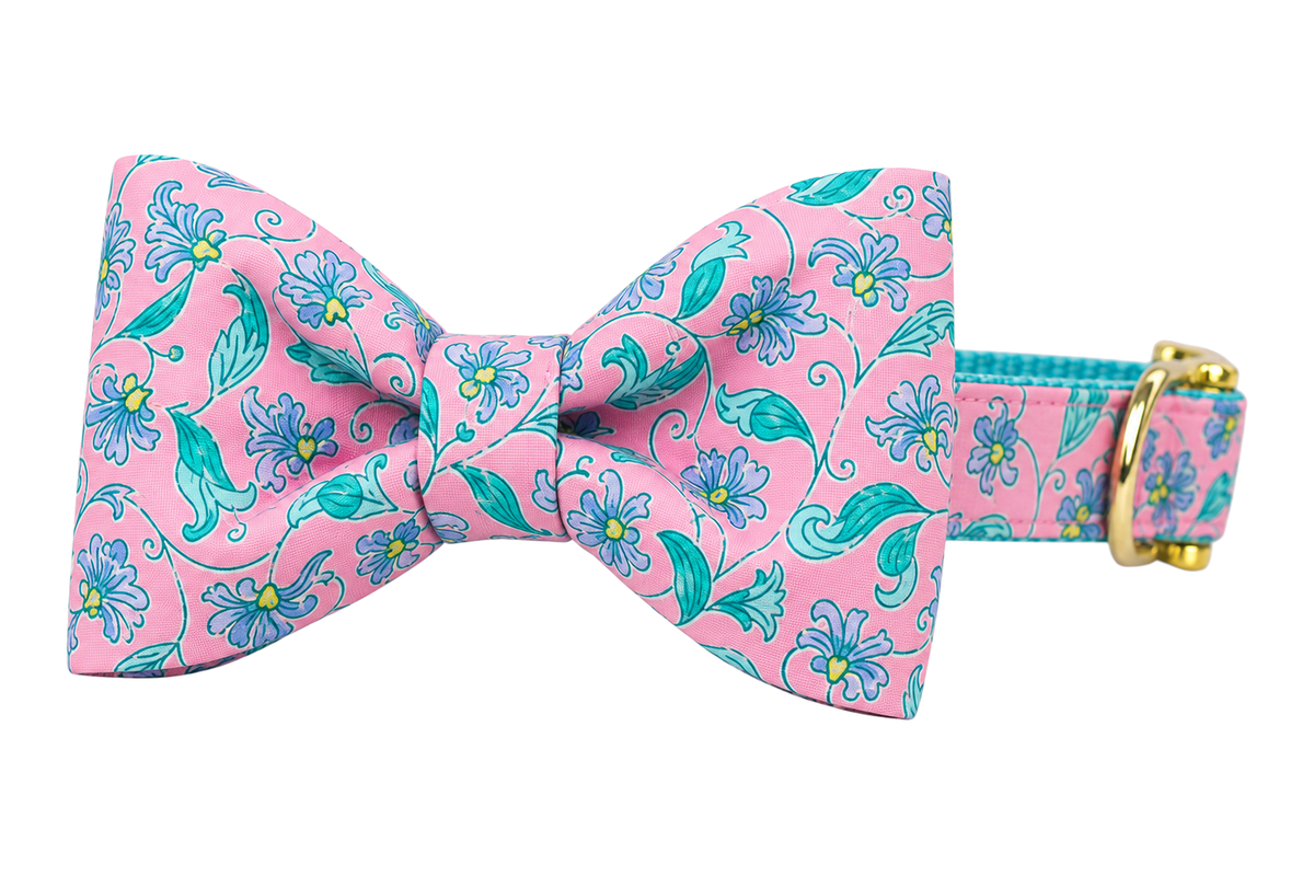 Classic dog collar featuring a Garden Gate fabric bow tie, a pink print with teal and periwinkle blue flowers and vines, attached to a matching Garden Gate collar with a nylon inner lining and gleaming gold hardware, including a D-ring and buckle.