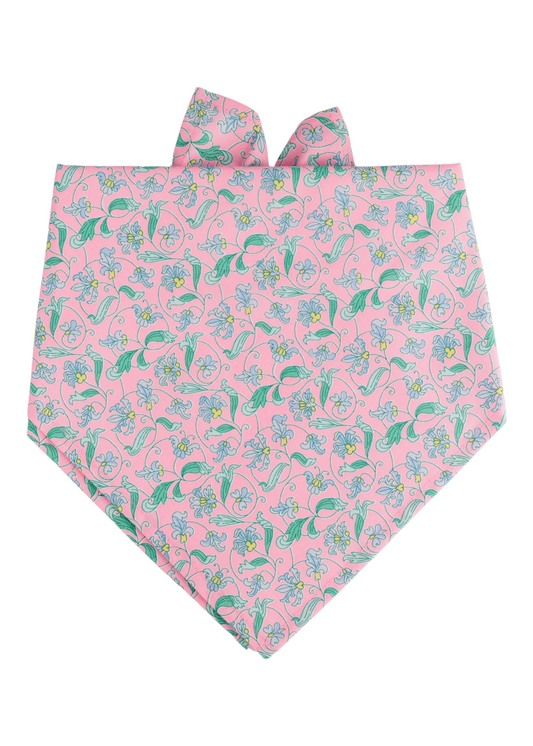 Dog bandana in soft pink fabric adorned with a repeating print of small blue blossoms, yellow-centered daisies, and leafy green vines. The bandana is shaped with a pointed bottom and finished with tie-up corners for a classic, adjustable fit.