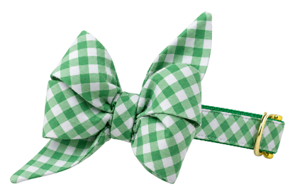Dog collar featuring a large belle bow in Garden Lattice fabric, a kelly green and white gingham check, attached to a matching Garden Lattice collar with a nylon inner lining and gleaming gold hardware, including a D-ring and buckle.
