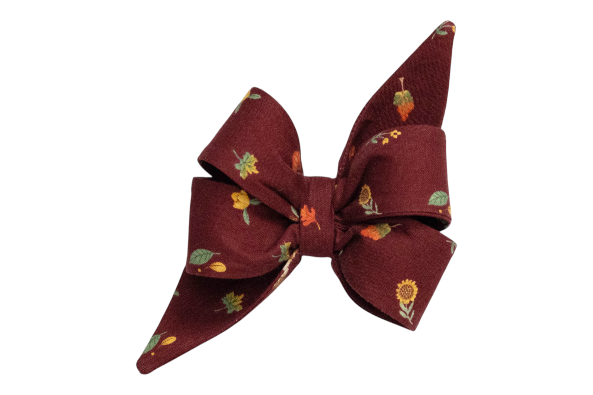 Feminine  maroon fabric belle bow featuring a festive fall print of seasonal foliage and florals, such as sunflowers, leaves, and berries.