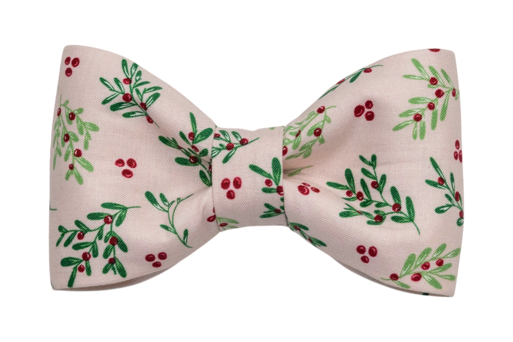 A classic dog bow tie made from light pink fabric with an all-over print of leafy sprigs and berries. The bow is neatly cinched at the center for a structured, symmetrical look.