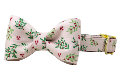 Festive dog collar with a matching bow tie, crafted from pale pink fabric decorated with clusters of berries and leaves. The bow tie is large and symmetrical, attached directly onto the collar. The collar includes shiny hardware, such as a D-ring and an adjustable clasp for sizing.