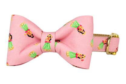 Classic dog collar featuring a Hula Girls fabric bow tie, a soft pink fabric with small hula girls in green grass skirts, attached to a matching Hula Girls collar with a nylon inner lining and gleaming gold hardware, including a D-ring and buckle.