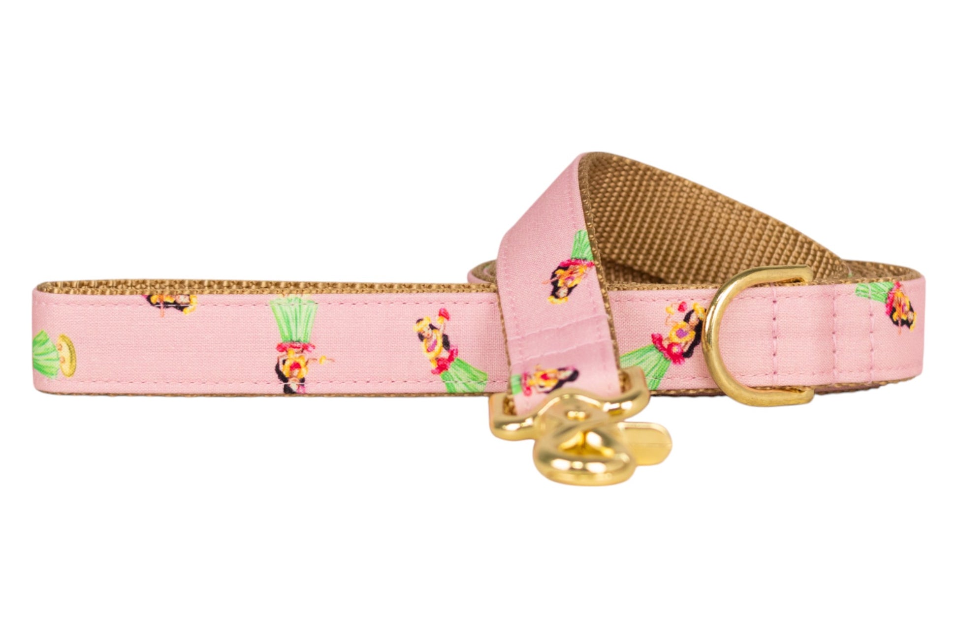 Pink dog leash with a tan underside, printed with hula dancers in green skirts and finished with gold-tone hardware. Perfect for summer.