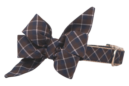 Elegant dog collar with a matching, large, feminine belle bow composed of multiple folded and pointed loops in a navy blue and brown argyle plaid print. The collar includes nylon webbing and a sturdy silver metal buckle, and a D-ring for leash attachment.