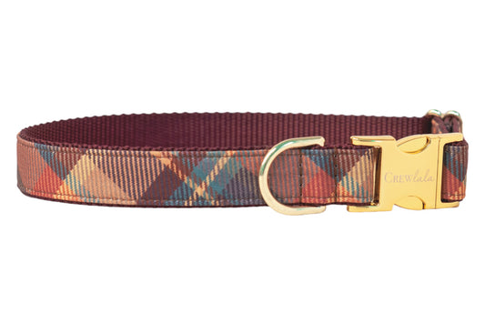 Plaid-patterned dog collar in warm, earthy tones with a nylon maroon lining, metal hardware, and the “Crew LaLa” logo engraved on the buckle.
