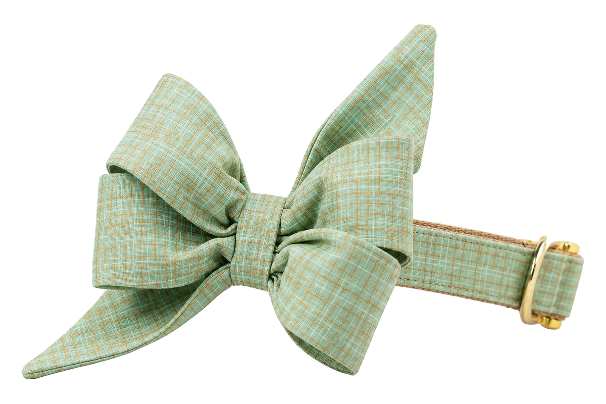 Dog collar featuring a large belle bow in Jadeite Green fabric, a soft jadeite mint green linen with a fine tonal plaid weave, attached to a matching Jadeite Green collar with a nylon inner lining and gleaming gold hardware, including a D-ring and buckle.