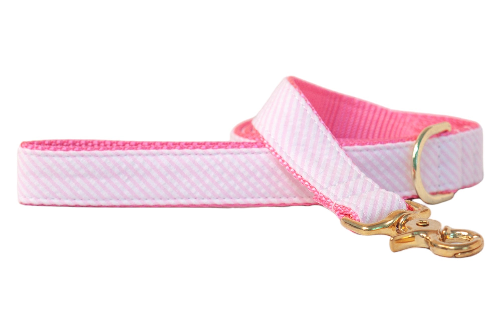 Pink and white seersucker fabric dog leash featuring diagonal candy stripe detailing, reinforced hot pink webbing on the reverse, and gleaming gold-tone metal components—perfect for stylish walks with your pup.