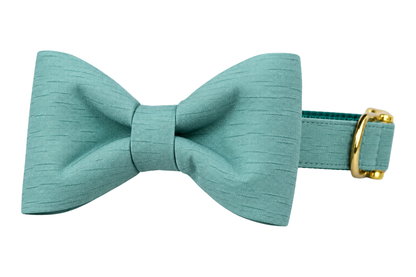 Classic dog collar featuring a Make Waves fabric bow tie, a solid seafoam teal shantung with a subtle slub texture, attached to a matching Make Waves collar with a nylon inner lining and gleaming gold hardware, including a D-ring and buckle.