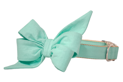 A mint green fabric girl dog belle bow attached to a matching collar, featuring soft, symmetrical loops and a smooth, minimalist design. The collar includes a silver D-ring and a matching side-release buckle.