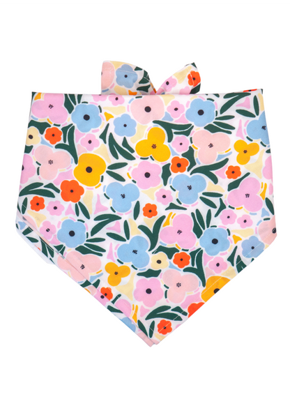 A soft cotton dog bandana with a white base and a dense pattern of multi-colored flowers—featuring soft pastels and bold hues in pink, orange, yellow, and blue—with leafy green accents. 