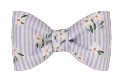 A fabric dog bow tie with vertical lavender and white stripes, decorated with a delicate floral print of white flowers and green leaves.