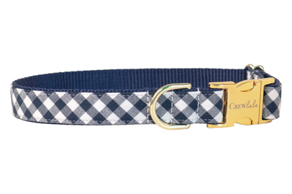 Classic navy plaid check dog collar with durable stitching and a blue webbed interior. Includes a curved metal buckle for quick fastening and a matching D-ring for tags or leash connection.