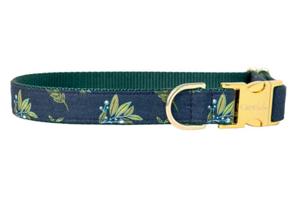 Stylish dog collar in dark blue with a leafy botanical print, paired with a dark inner webbing and metal hardware, including a buckle engraved with “Crew Lala.”