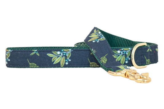 Dog leash with a dark navy fabric patterned with leafy branches and small berries, lined with textured dark nylon webbing, and finished with metal hardware including a clasp and D-ring.