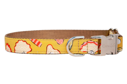 Yellow fabric dog collar with citrus wedges, stylized oysters with wavy pink-edged shells. The collar is lined with tan webbing and fitted with silver-tone hardware, including a secure side-release buckle and D-ring.