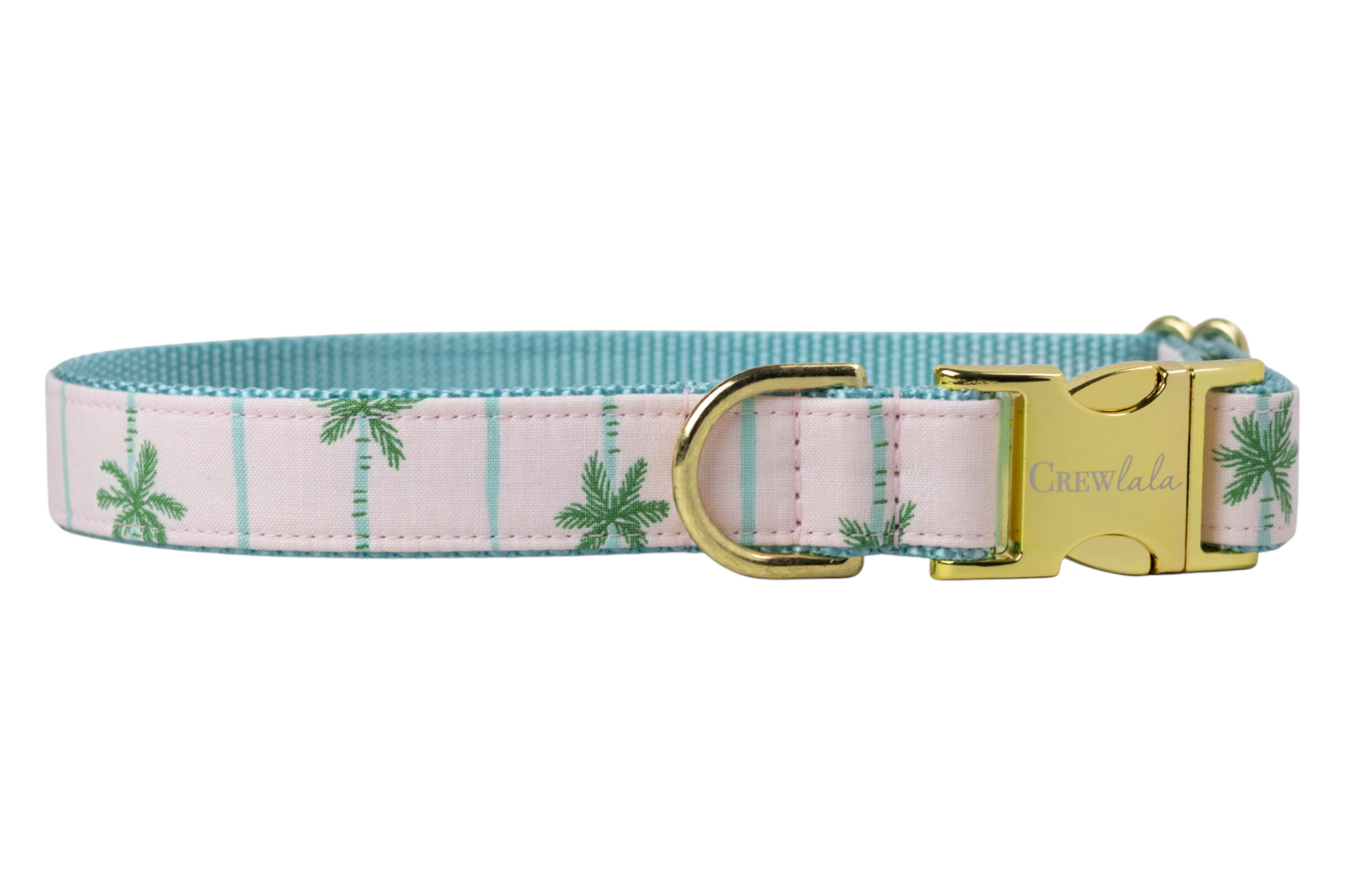 Tropical-themed dog collar decorated with green palm tree prints on a light pink background, complemented by gold hardware and a blue woven interior. 