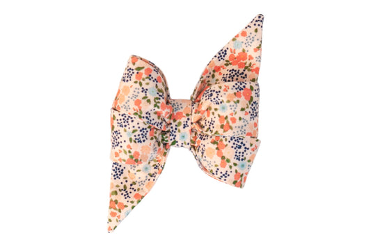 Oversized dog belle bow featuring a peach background covered in small flowers accented with leafy details, shaped with two pointed ends giving it a feminine style.