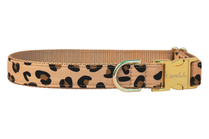 Stylish dog collar featuring a tan fabric with bold leopard spots, metal hardware, and a sleek nylon webbing backing—perfect for pups with glam instincts and wild hearts.