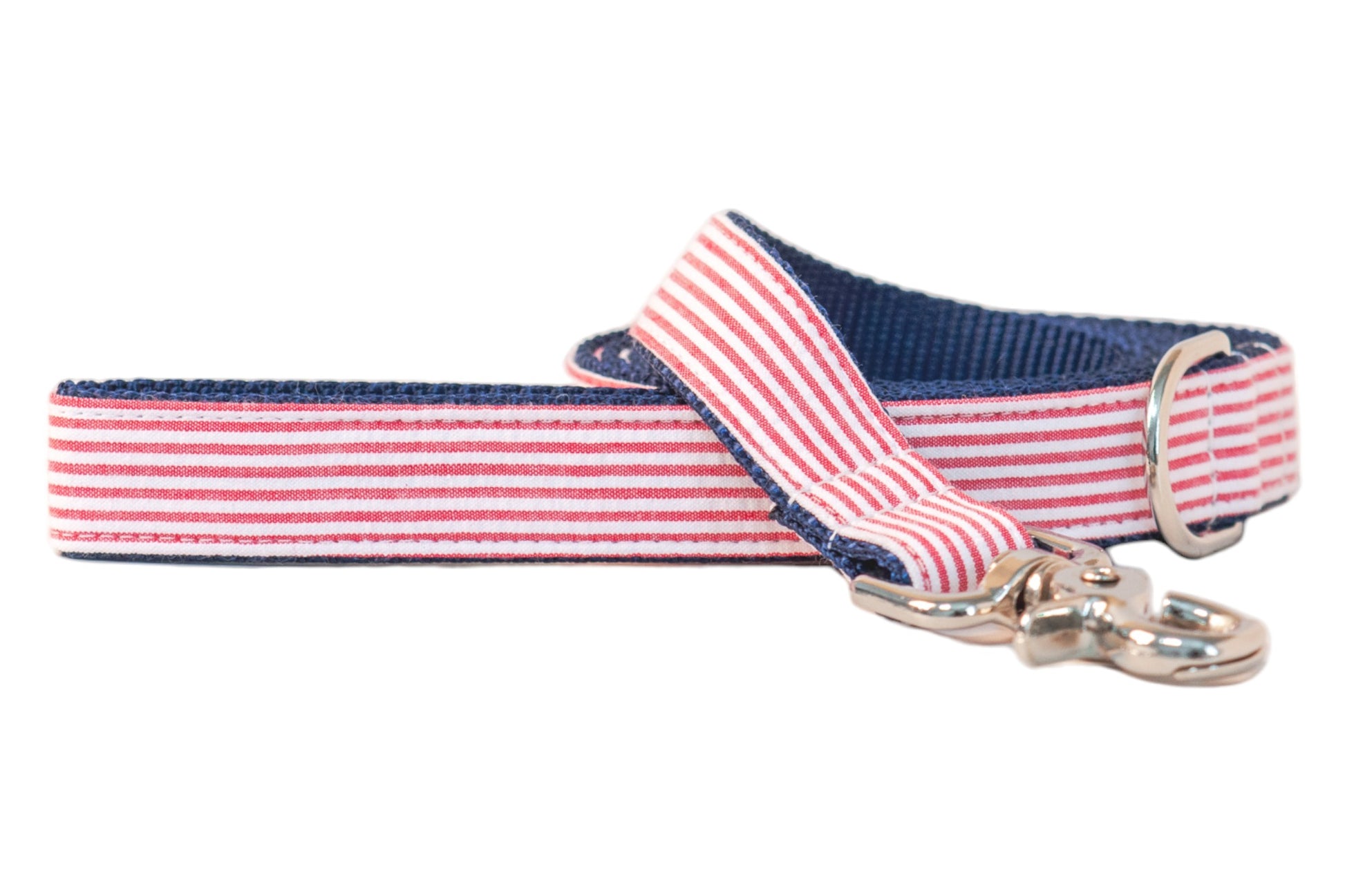 Patriotic-themed dog leash with a red-and-white striped seersucker front, navy blue interior webbing, and a shiny silver clip hook, blending classic Americana style with durable construction.