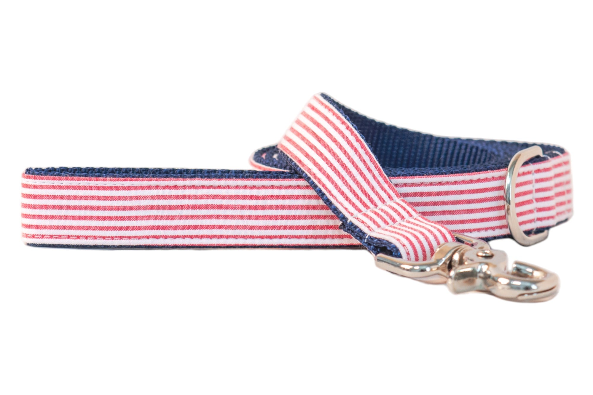 Patriotic-themed dog leash with a red-and-white striped seersucker front, navy blue interior webbing, and a shiny silver clip hook, blending classic Americana style with durable construction.