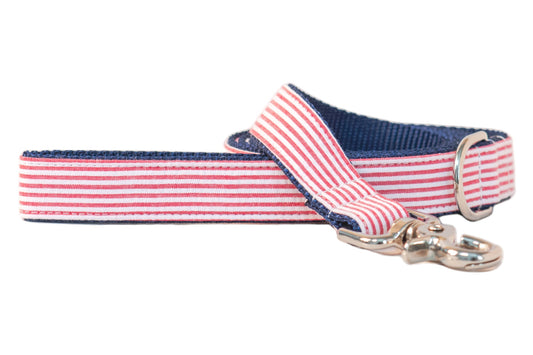 Patriotic-themed dog leash with a red-and-white striped seersucker front, navy blue interior webbing, and a shiny silver clip hook, blending classic Americana style with durable construction.