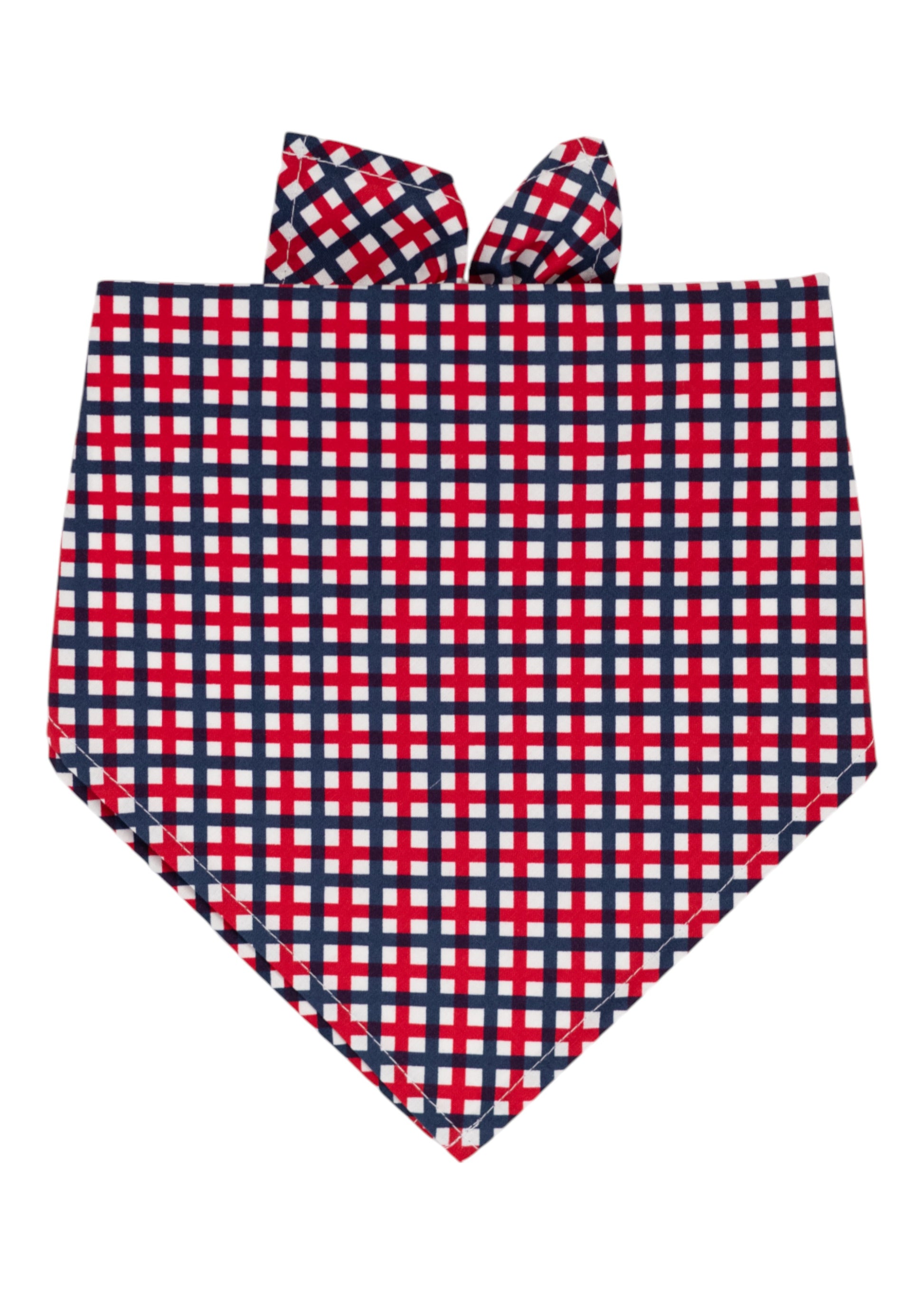 A patriotic themed dog bandana with a red, white, and navy blue plaid pattern, folded into a triangular shape with tie-up ends at the top. 