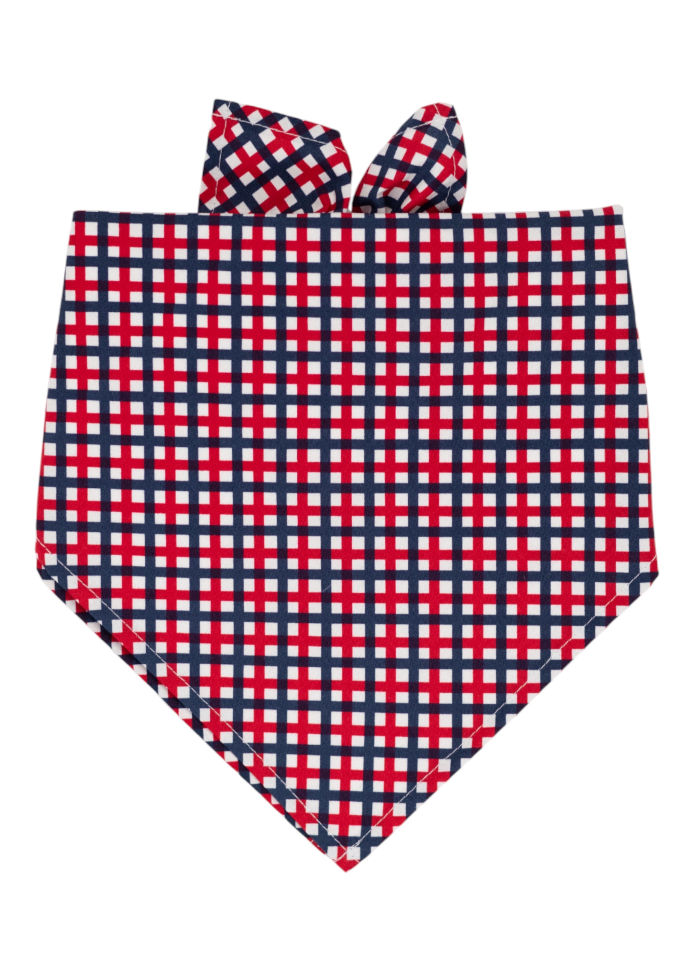 A patriotic themed dog bandana with a red, white, and navy blue plaid pattern, folded into a triangular shape with tie-up ends at the top. 