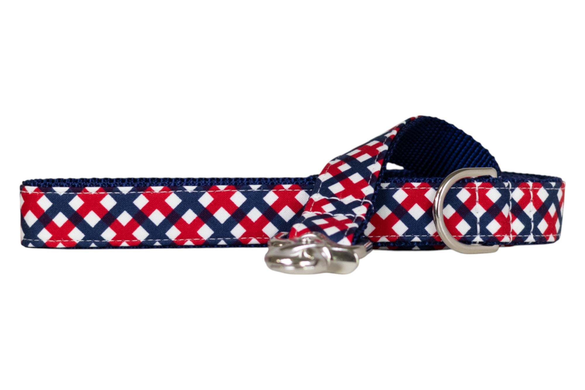 A patriotic red, white, and navy blue plaid dog leash with a crisscross checkered design, featuring reinforced stitching along the edges, a metal D-ring, and a polished clasp for secure attachment.