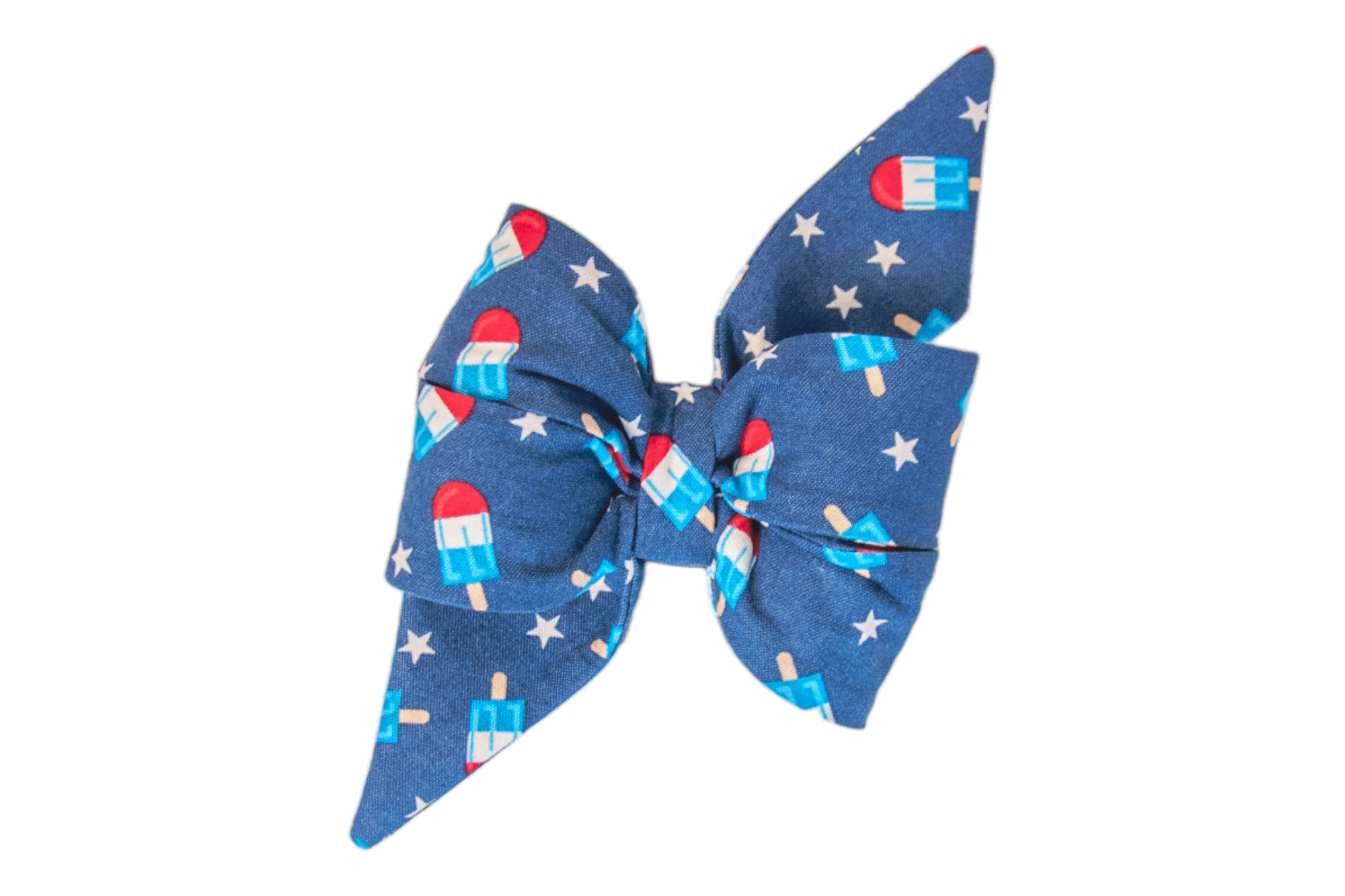 Close-up of a decorative feminine dog belle bow featuring a vivid blue fabric covered in red, white, and blue popsicles, interspersed with white stars. The bow has a voluminous, tied design with neatly folded loops and two pointed tails, giving it a crisp and celebratory appearance.