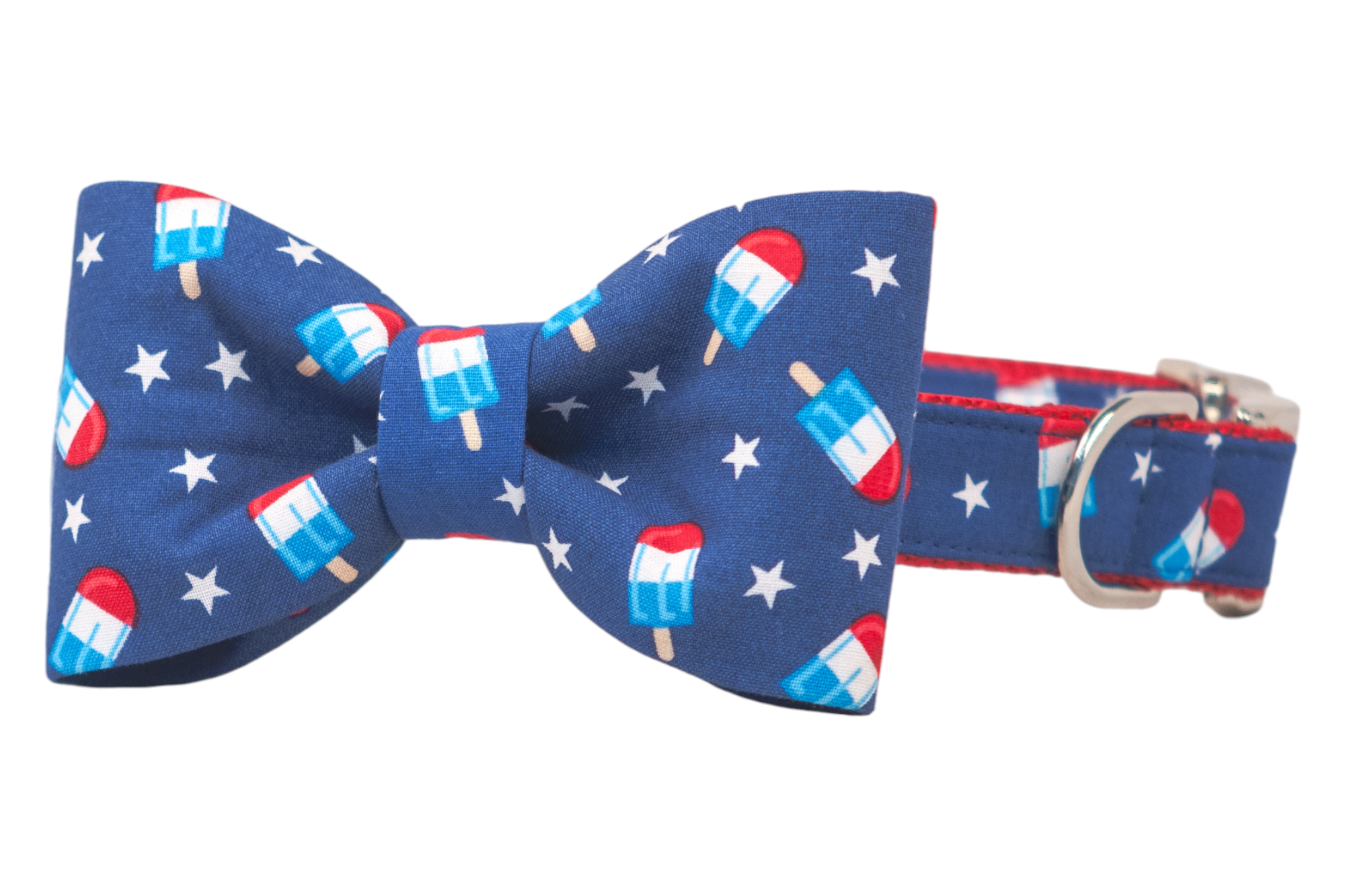 Patriotic-style dog collar and bow tie set made from blue fabric printed with rocket popsicles and white stars. The bow tie is neatly centered on a matching collar, which features red webbing, a secure metal buckle, and a polished silver D-ring for tags or leash clips.
