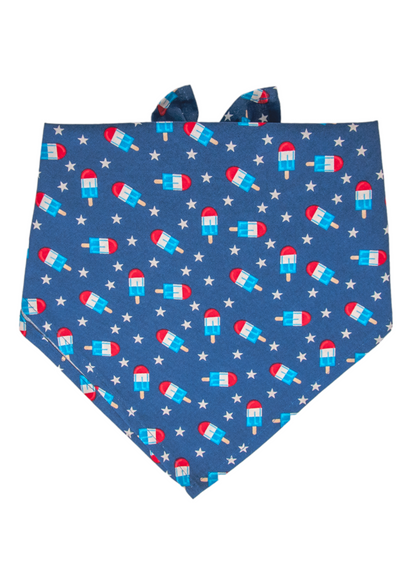 A patriotic-themed dog bandana with a vivid blue background, decorated with red, white, and blue popsicles and scattered white stars. 