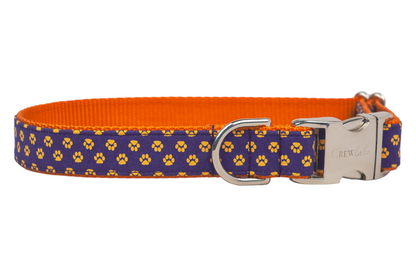 A bold and playful dog collar designed with paw prints on deep navy and lined with bright nylon webbing. Complete with a polished buckle and D-ring for durability and flair.