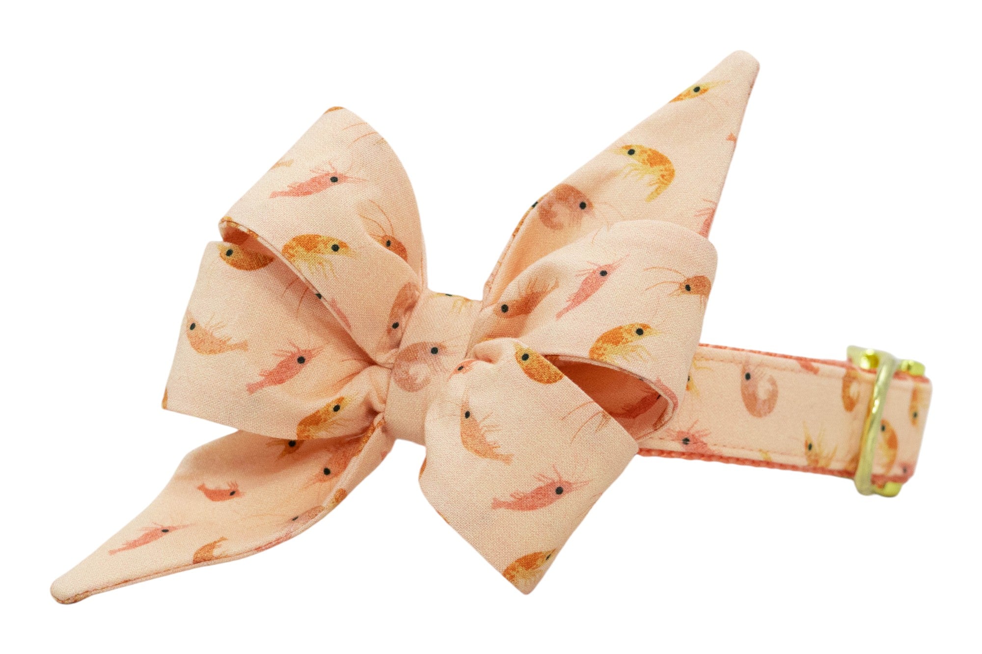 Soft peach dog collar with a fabric bow accent, patterned with warm-toned shrimp and finished with gold metal hardware.