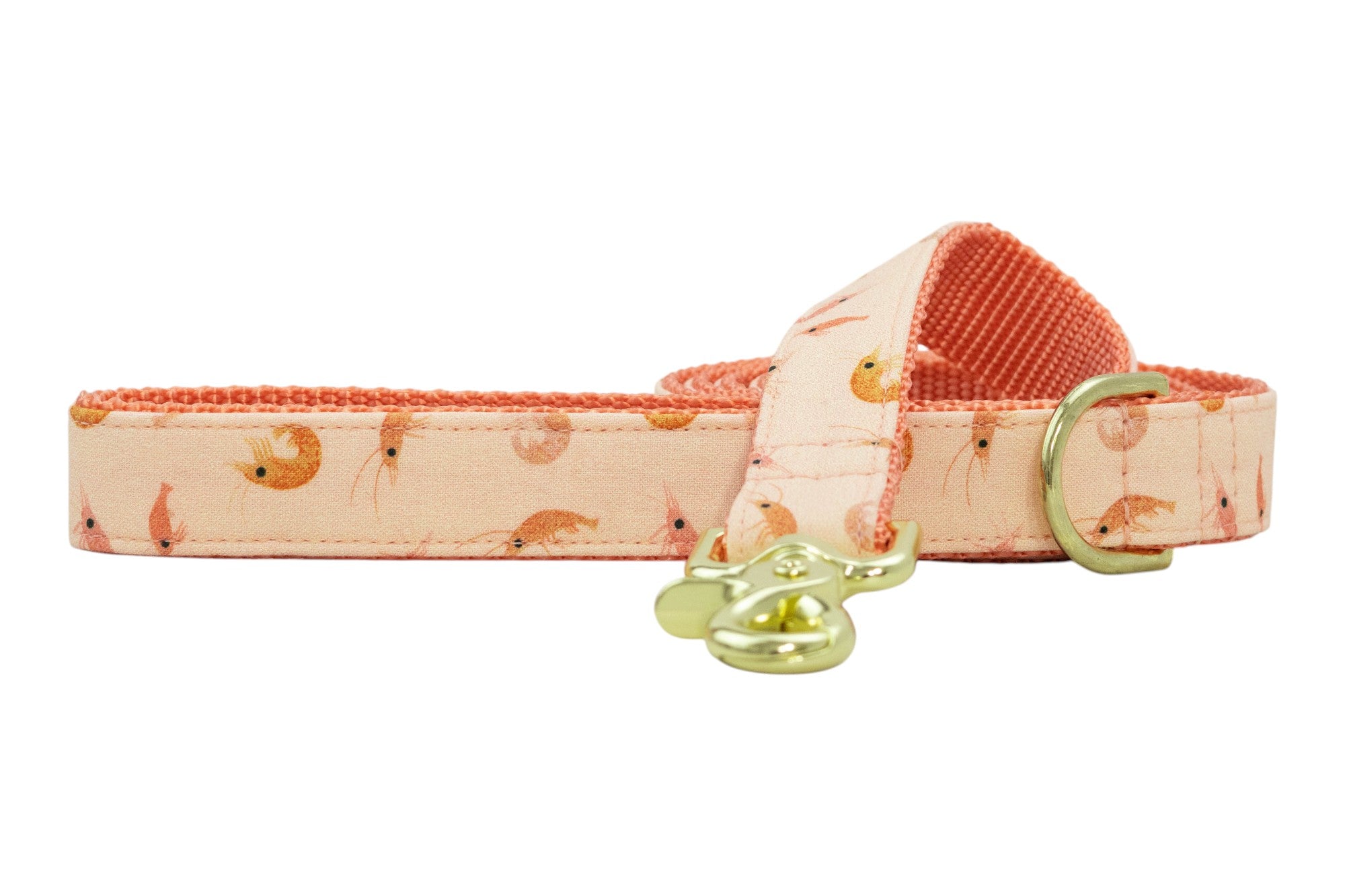 Peach-colored dog leash with small shrimp illustrations and coral padded underside, featuring gold-tone clasp and D-ring.