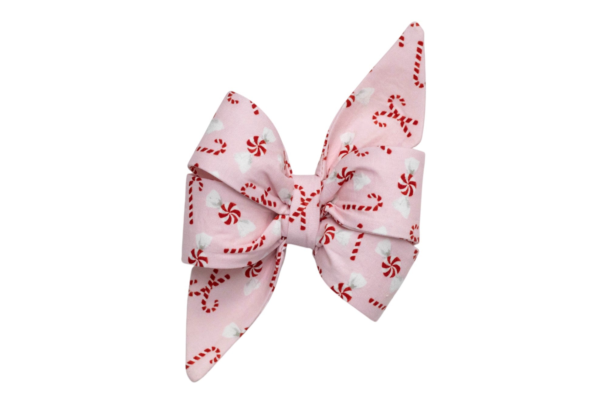 An oversized dog belle bow made from pink fabric with candy canes and peppermint swirls. The bow features large, structured loops and long, pointed tails, creating a bold and festive accessory perfect for holiday wear.