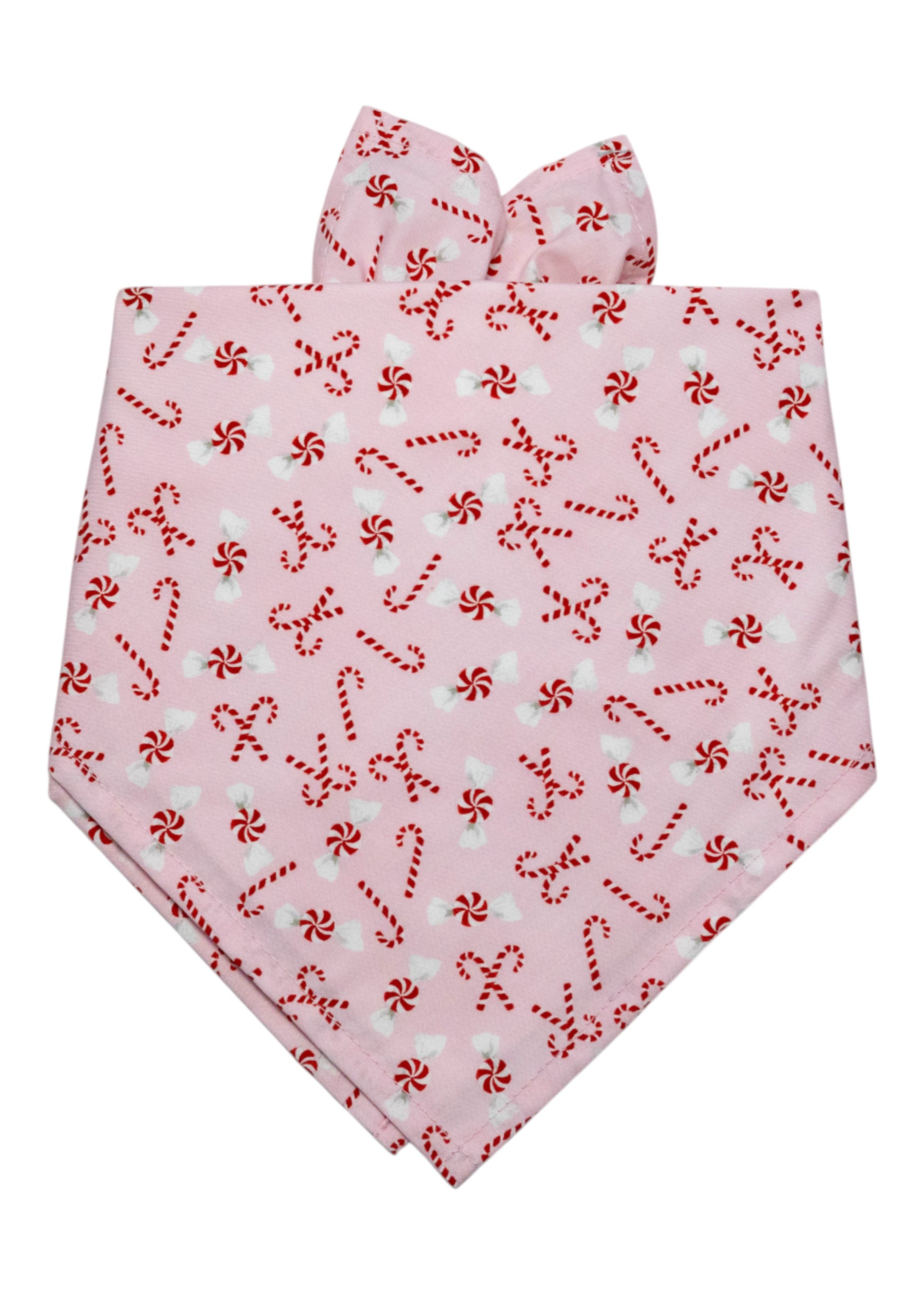 Festive dog bandana in a pastel pink color, with candy canes and peppermint candies. Designed for tying around the neck.