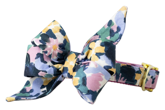 A floral dog collar with an attached matching belle bow in a watercolor-style floral print. The belle bow has pointed tails and layered loops, and the collar includes metal hardware.