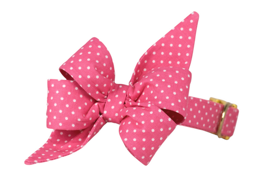 Pink dog collar with a large, double-looped belle bow featuring pointed tails, all in a white polka dot pattern, secured with gold-tone hardware.