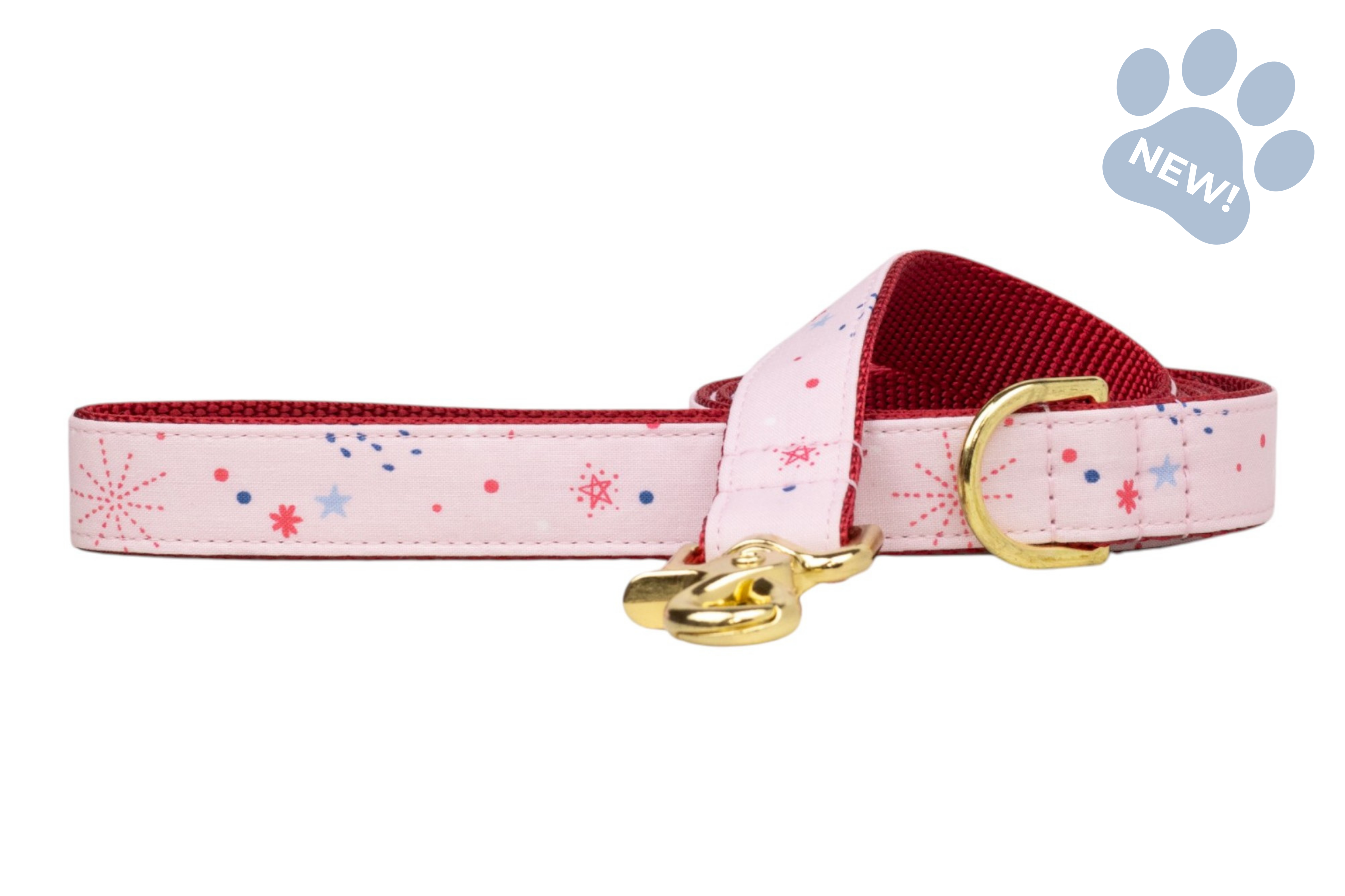 Pastel pink pet leash decorated with small red and blue starburst prints, lined in red and finished with gold hardware.
