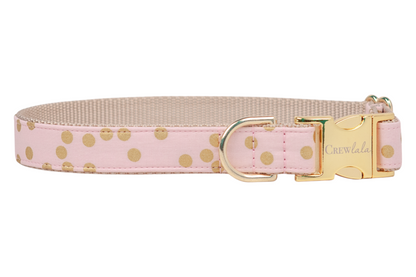 Elegant pink dog collar patterned with shiny gold dots, backed by woven nylon for durability. It’s finished with gold-tone hardware including a branded buckle and a sturdy D-ring.