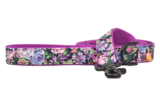 A stylish, dog leash with a lively floral design and backed with textured purple nylon webbing. The leash includes a metal clip and D-ring, combining fashion with function.