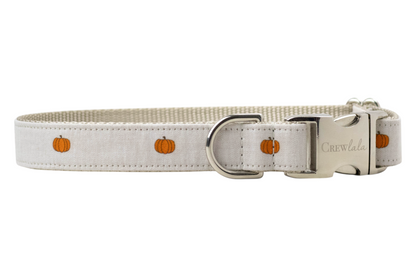 Adjustable dog collar with a beige outer fabric printed with small, evenly spaced pumpkins. The collar features a tan woven interior, a side-release buckle engraved with “Crewlala,” and a matching D-ring. A cozy and refined option for fall or Halloween.