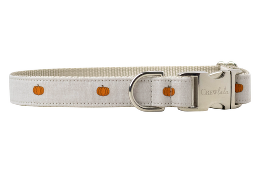 Adjustable dog collar with a beige outer fabric printed with small, evenly spaced pumpkins. The collar features a tan woven interior, a side-release buckle engraved with “Crewlala,” and a matching D-ring. A cozy and refined option for fall or Halloween.