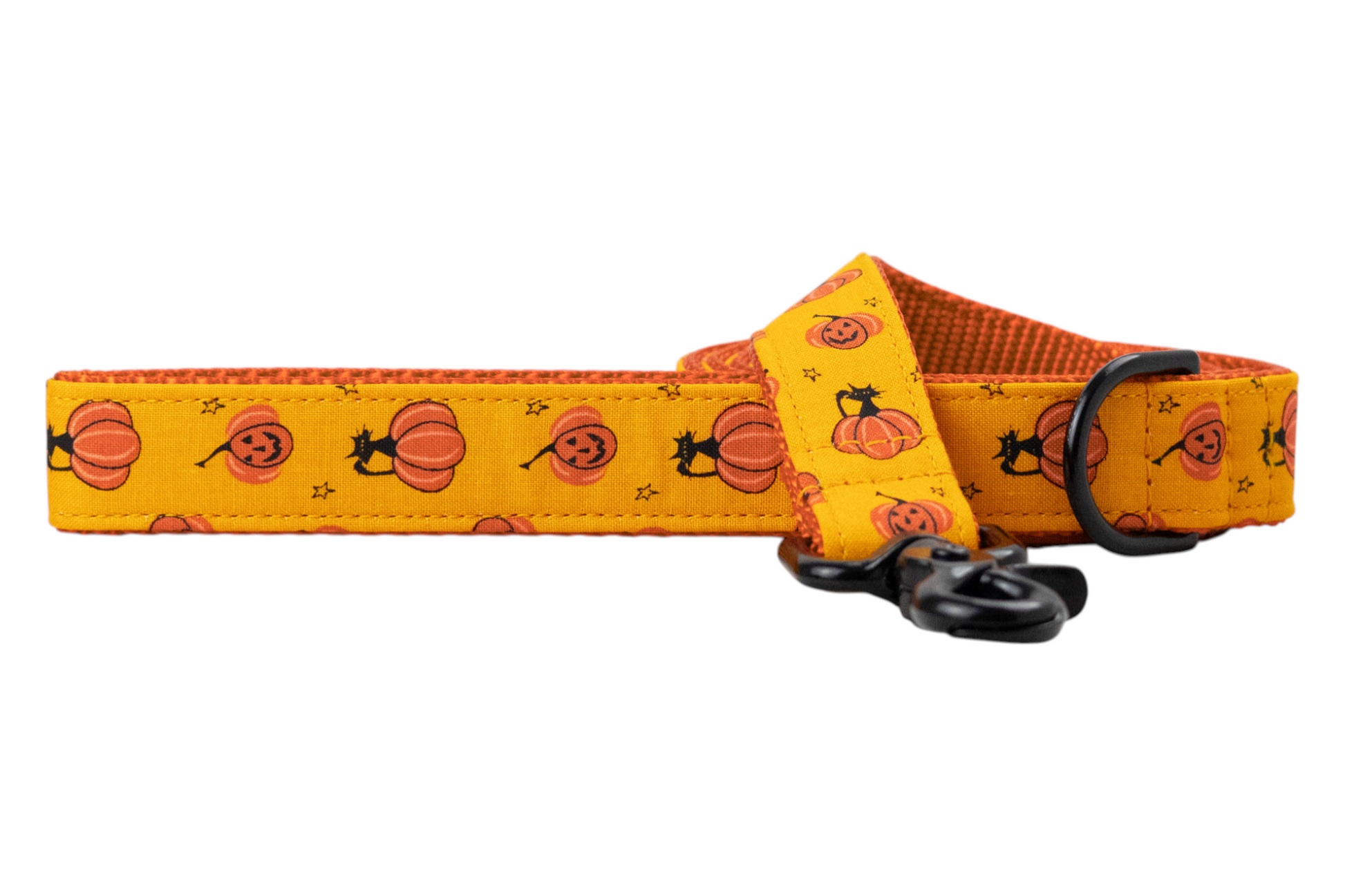 Close-up of a Halloween-themed dog leash with playful jack-o'-lanterns and cat silhouettes on a vivid orange fabric, fitted with metal hardware.