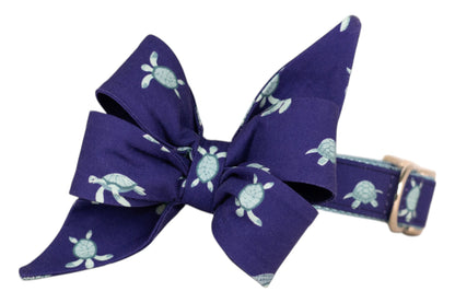 Navy dog collar with a playful sea turtle print in light turquoise, complemented by a  matching large structured bow and a polished metal buckle.