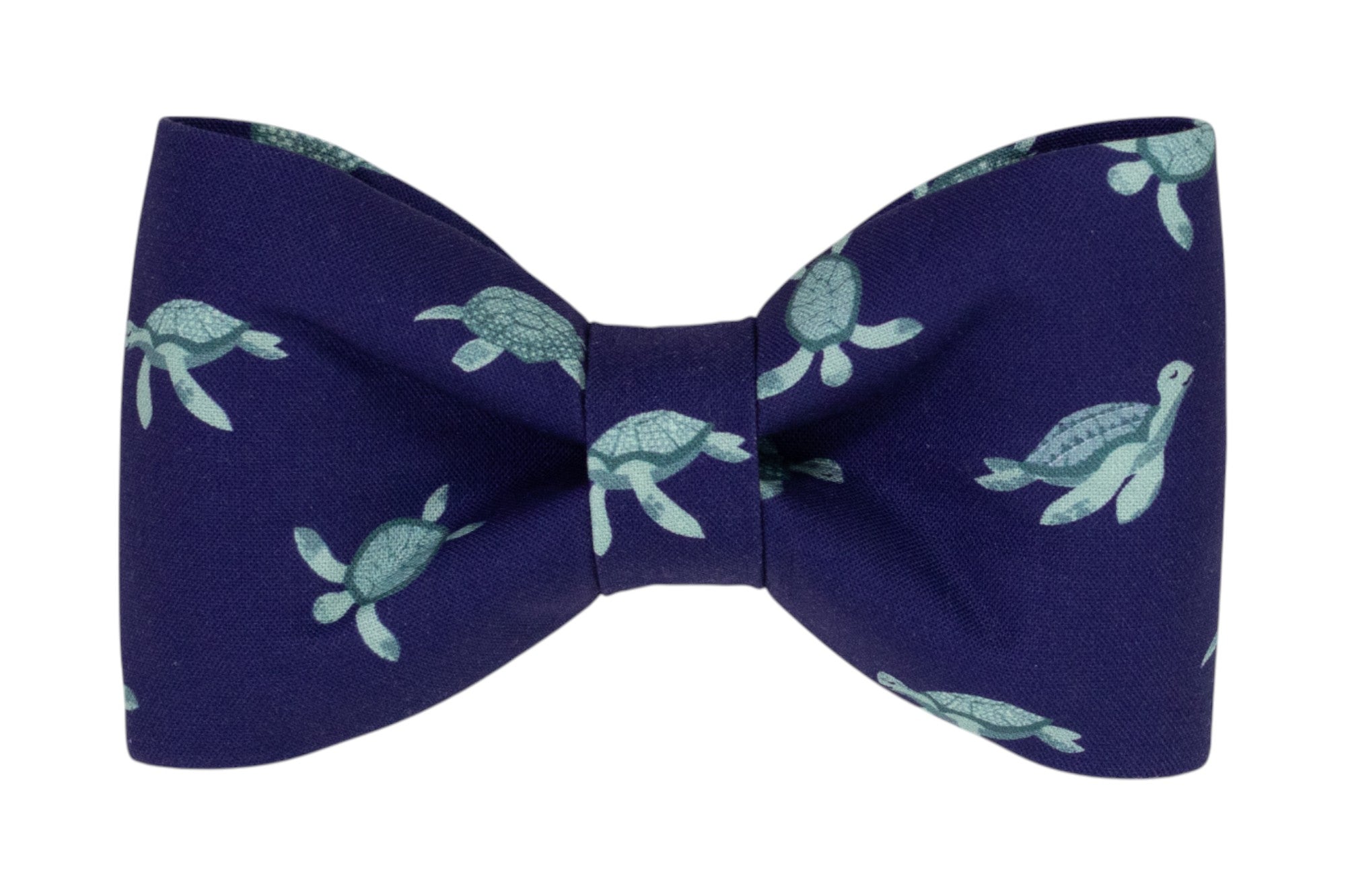 A deep navy fabric dog bow tie decorated with a light turquoise sea turtle pattern. The turtles are illustrated in a swimming pose, scattered evenly across the fabric.