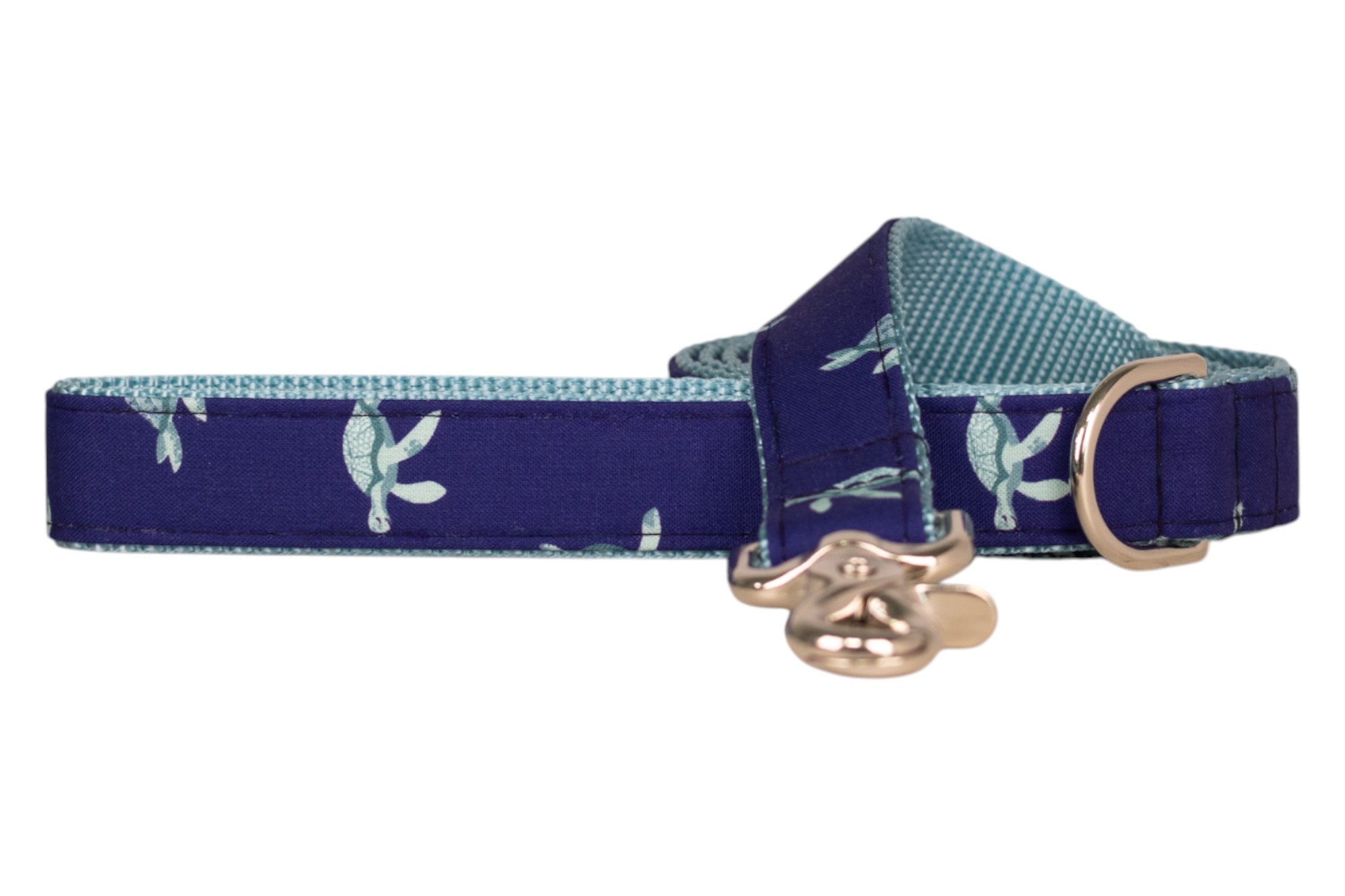 Nautical-themed dog leash in dark navy, decorated with turquoise sea turtles. It has a light blue turquoise nylon interior, a metallic D-ring, and a shiny  clasp for secure attachment.